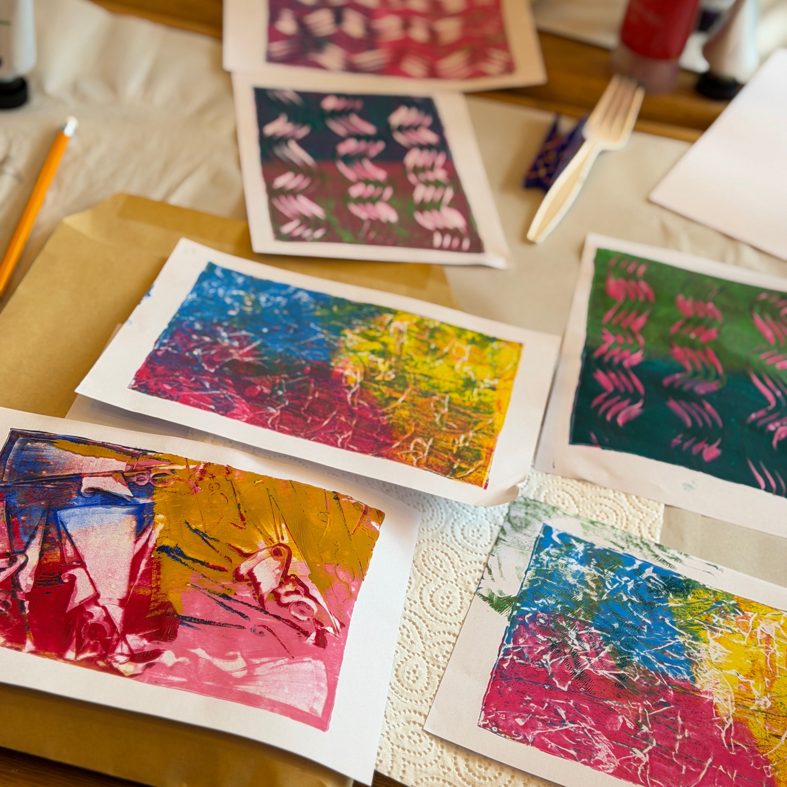 Colorful art prints on a table with stationery items.