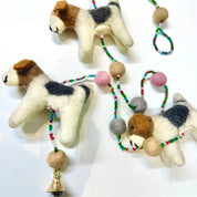 Three felted dog toys with bead and bell decorations on a white background