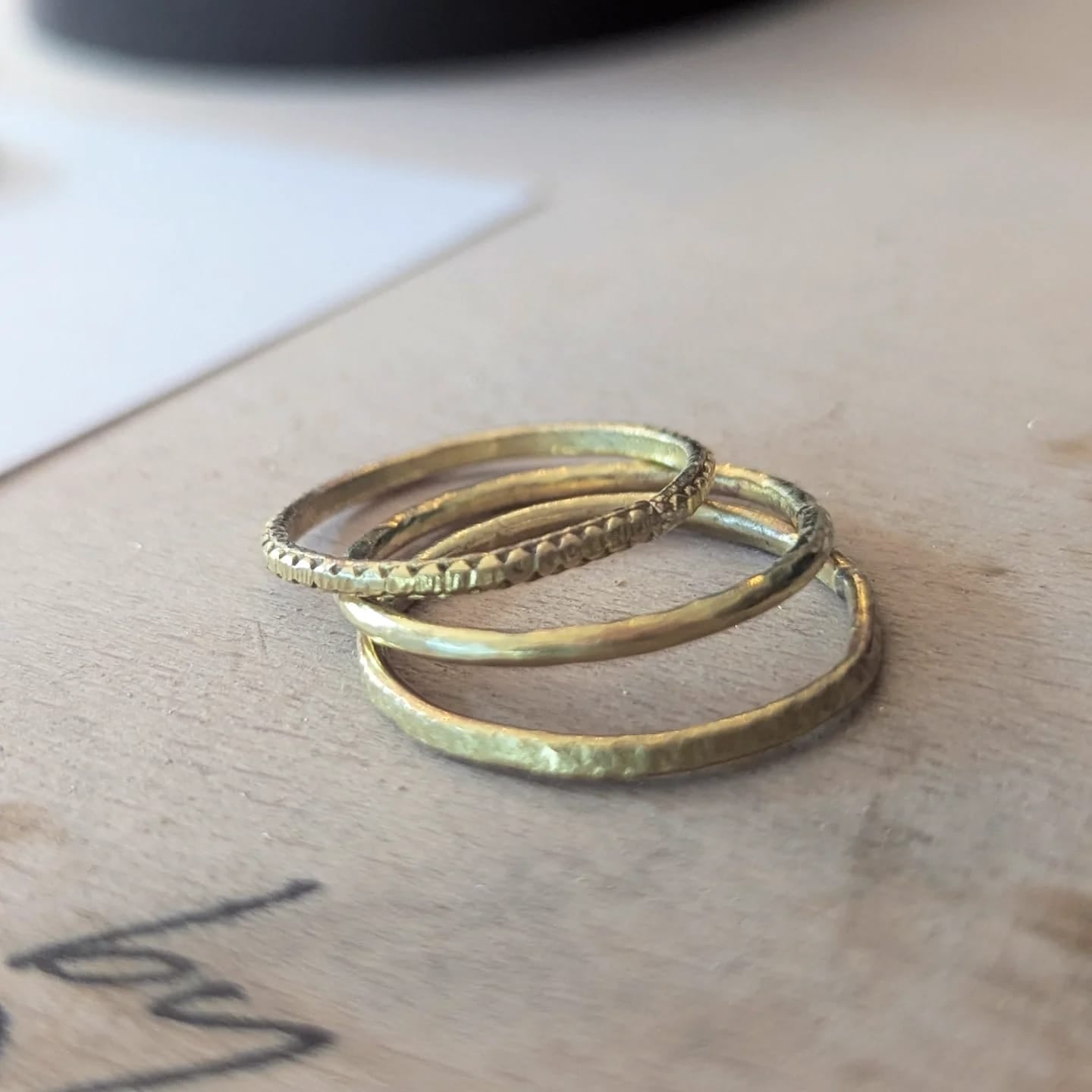 Two gold rings stacked on a wooden surface with a blurred background