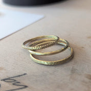 Two gold rings stacked on a wooden surface with a blurred background