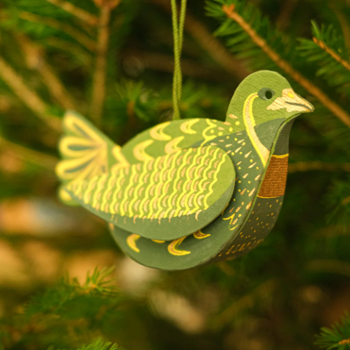 Green and gold bird-shaped ornament hanging on a tree