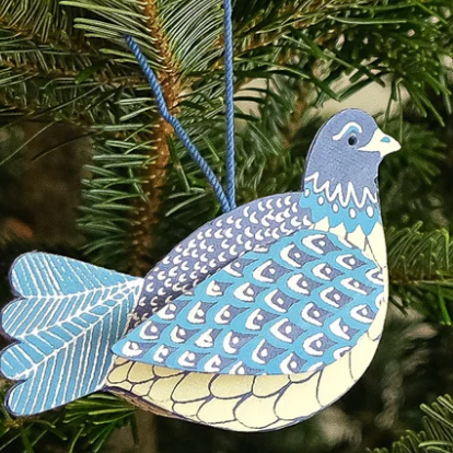 Decorative blue bird ornament hanging on a Christmas tree.