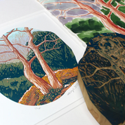A product listing showing a set of rustic, irregularly shaped wooden art prints featuring hand-painted forest and tree designs. The main image displays three circular and oval prints fanned out on a white surface, with smaller thumbnails below showing a hand holding a print and close-ups of the wood grain.