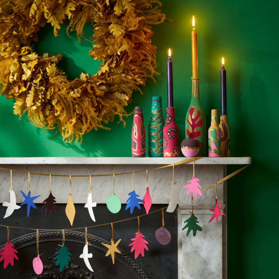 A screenshot of a web browser showing an article about making fun and bright mason jar candles, with a featured image of a decorated mantel featuring colorful mason jars, a gold wreath, and hanging star ornaments.