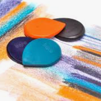 Four small teardrop-shaped colored pencil erasers in orange, black, blue, and purple, arranged on top of a colorful painted surface with visible pastel brushstrokes.