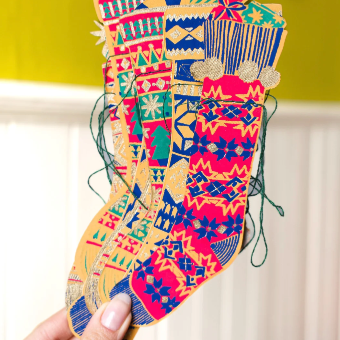 A computer desktop screenshot showing a product page for a festive stocking sewn with embroidery thread. The page displays a close-up of a colorful embroidered stocking held by a hand, along with product details and smaller thumbnail images.
