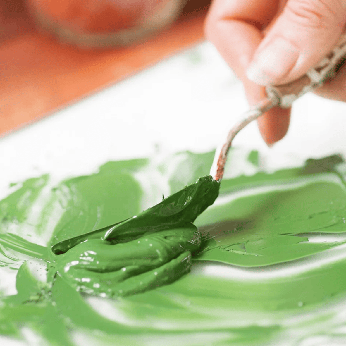 A screenshot of an e-commerce product page for the Natural Earth Paint Complete Eco-Friendly Artist Oil Paint Kit. The page features a product photo of a hand painting with green oil paint, product details including a 100% natural oil and paint composition, and a list of included colors and tools.
