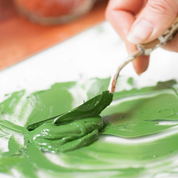 A screenshot of an e-commerce product page for the Natural Earth Paint Complete Eco-Friendly Artist Oil Paint Kit. The page features a product photo of a hand painting with green oil paint, product details including a 100% natural oil and paint composition, and a list of included colors and tools.