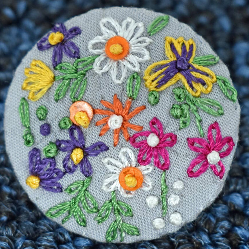 Embroidered patch with colorful flowers on a textured blue fabric background