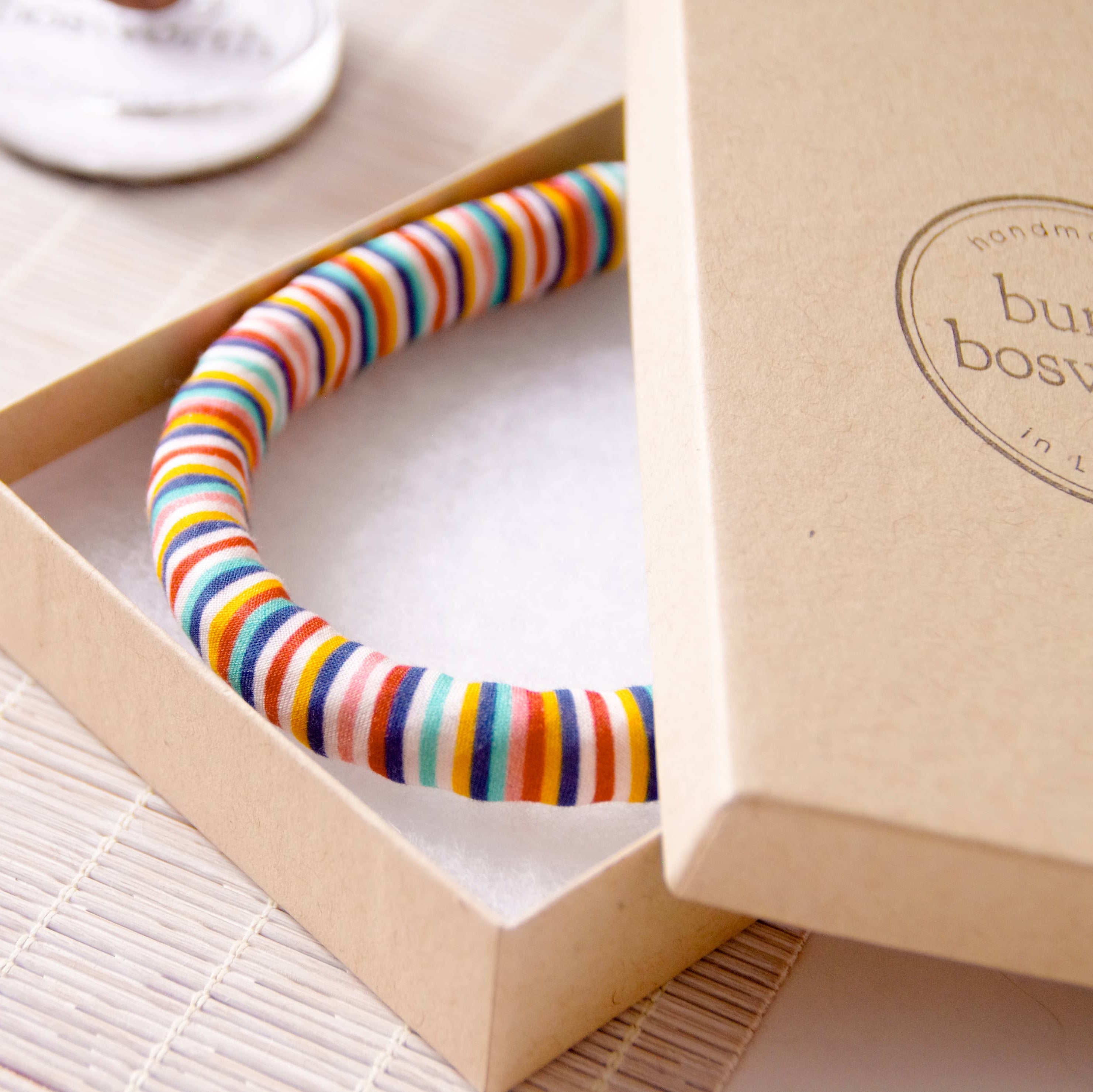 Colorful striped bracelet in a box on a light surface