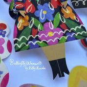 Colorful paper doll with floral dress and butterfly wings on a white background, featuring 'Butterfly Women by Kitty Kenda'.