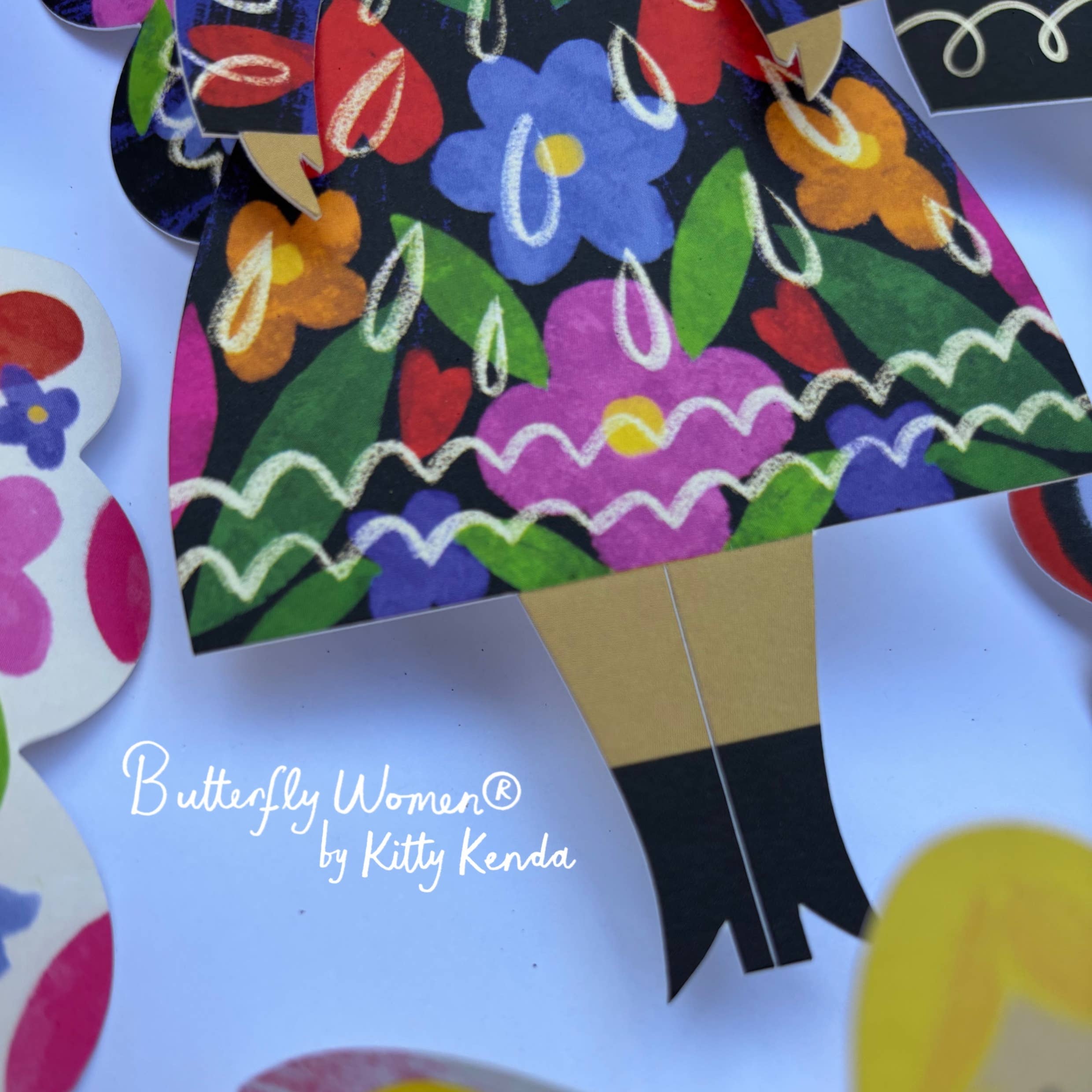 Colorful paper doll with floral dress and butterfly wings on a white background, featuring 'Butterfly Women by Kitty Kenda'.