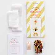 Cotton Clara embroidery cross-stitch kit with packaging, thread, and needle on a white background