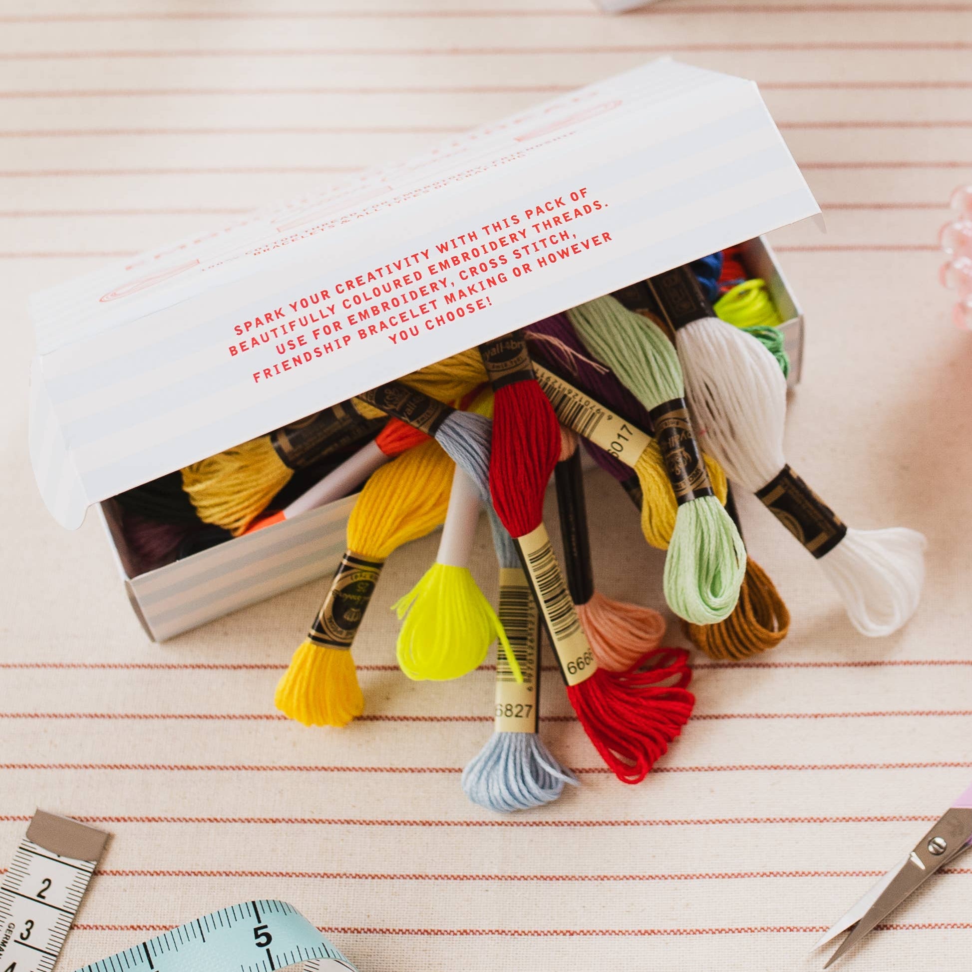 Embroidery thread set with colorful floss, scissors, and a measuring tape on a wooden surface.
