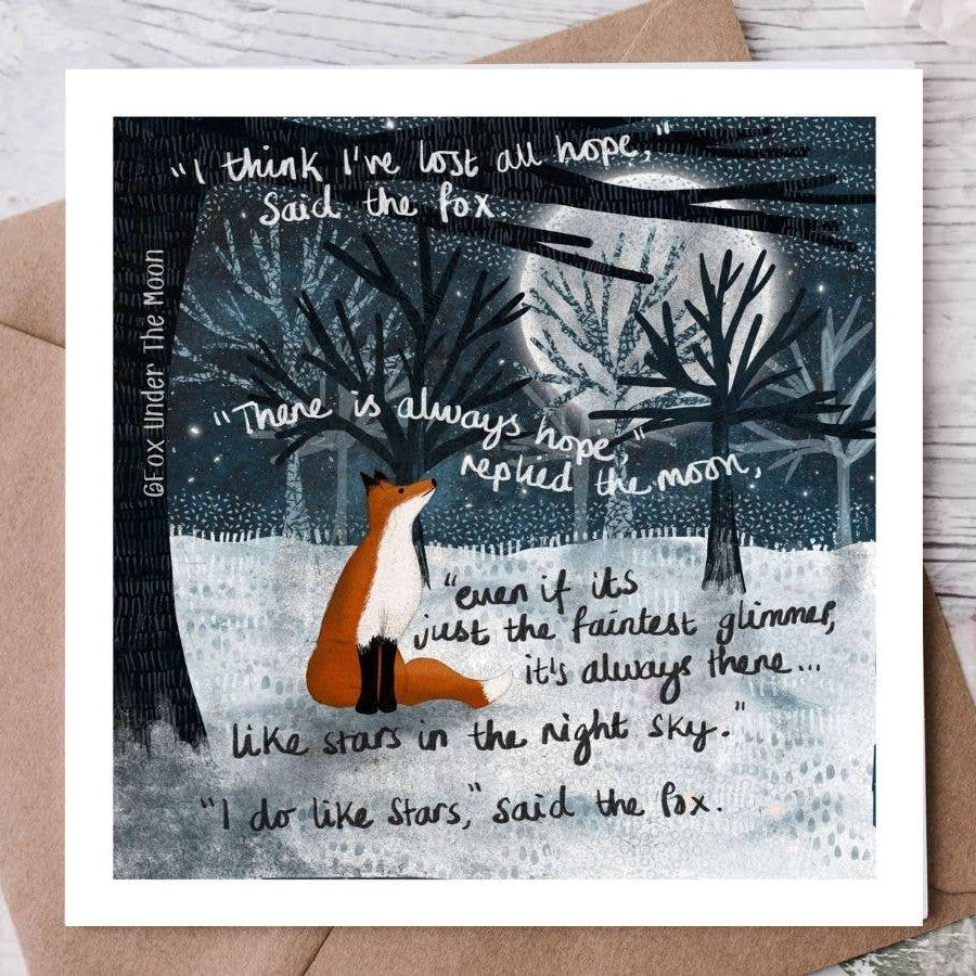 Greeting card with fox and moon illustration and text on a wooden surface