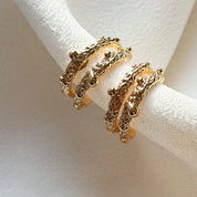 Gold hoop earrings on a white fabric background