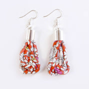 A pair of handmade dangle earrings featuring a red, white, and black floral patterned fabric wrapped in teardrop-shaped loops, suspended from silver-toned metal hooks on a plain white background.