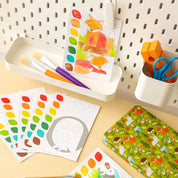 Colorful children's art supplies including paint, brushes, and coloring books on a table.