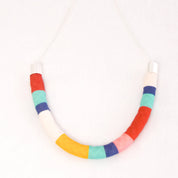 A handmade U-shaped necklace made of colorful fabric-covered segments in red, white, blue, yellow, pink, and mint green, hanging from a silver chain against a plain white background.