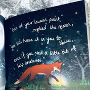 Open book with a fox illustration and moonlit night scene, held by a hand.