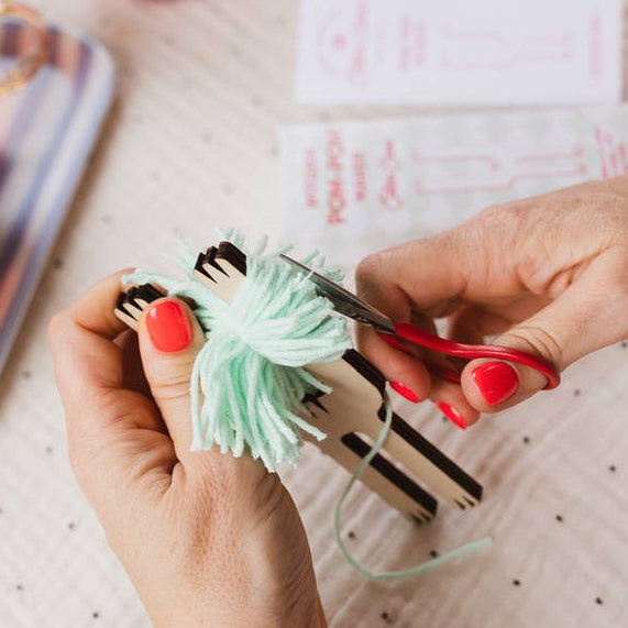 Person cutting yarn with scissors on a polka dot fabric background
