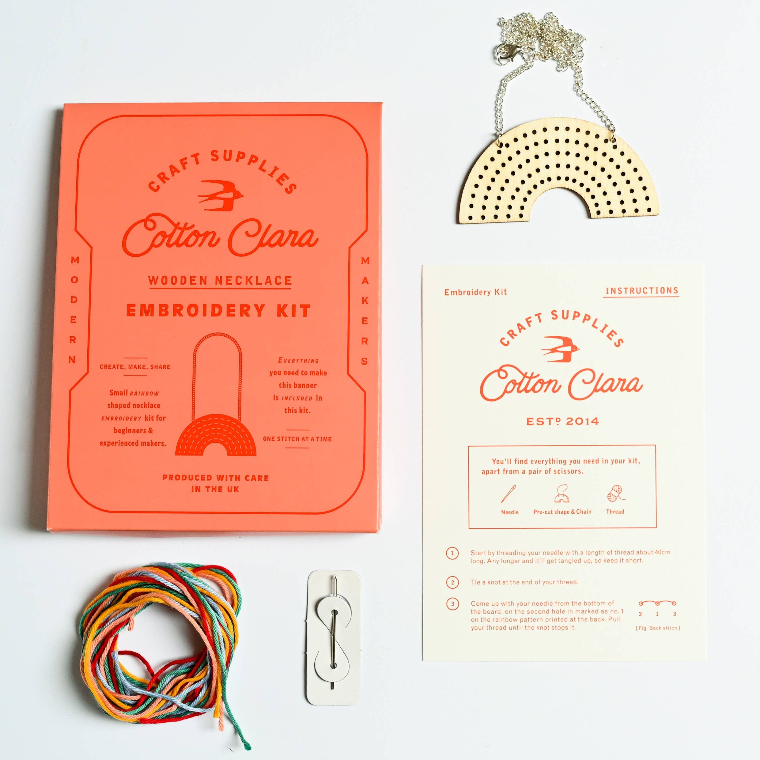 Cotton Clara embroidery kit with wooden necklace, yarn, and rainbow-shaped tool on a white background