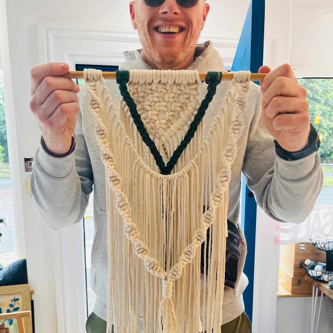Person holding a macrame wall hanging indoors