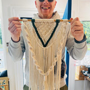 Person holding a macrame wall hanging indoors