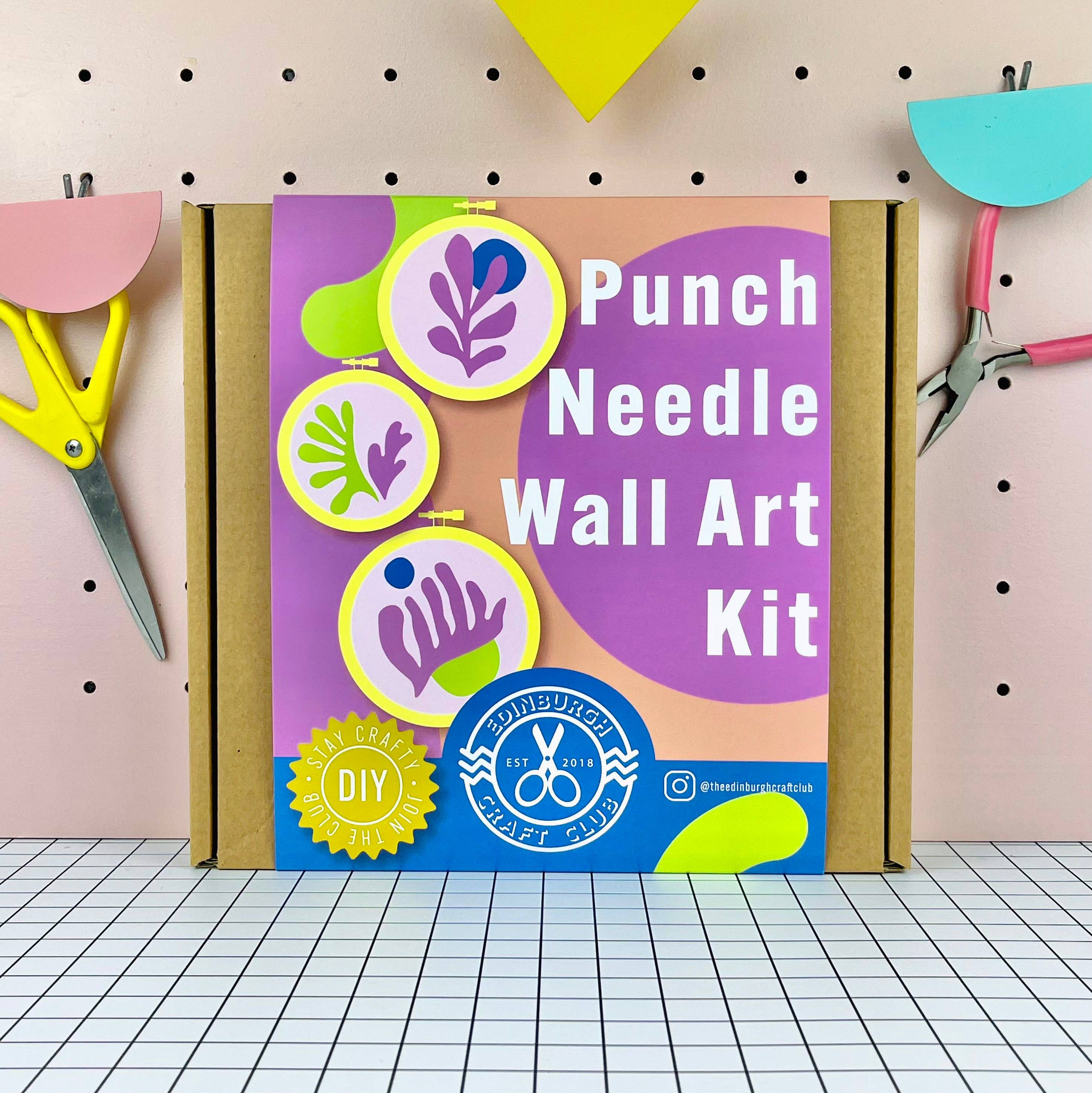 Punch Needle Wall Art Kit packaging with scissors and a ruler on a pegboard background
