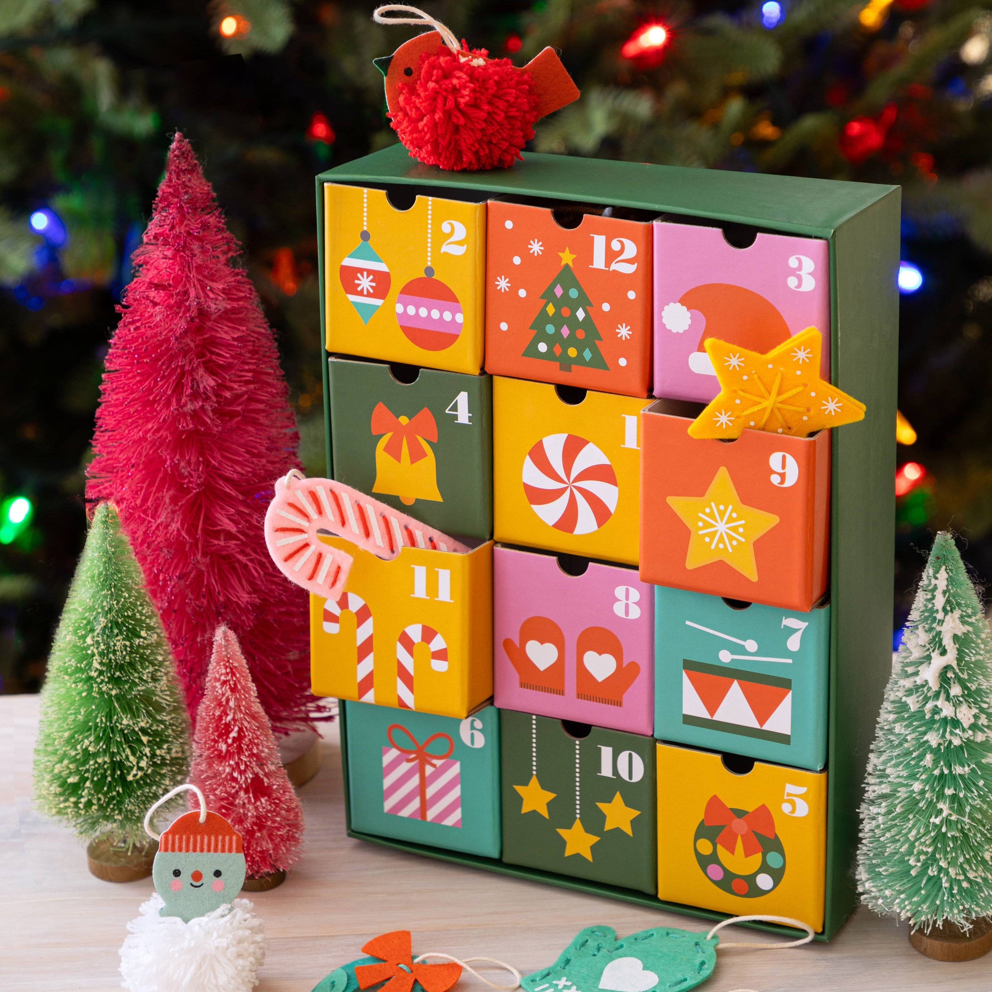 Colorful advent calendar with Christmas-themed decorations on a table with a festive background.
