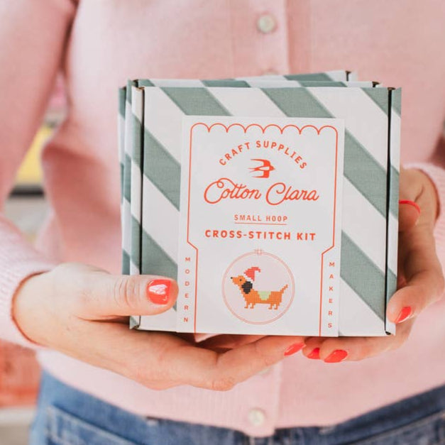Person holding a Cotton Clara cross-stitch kit box