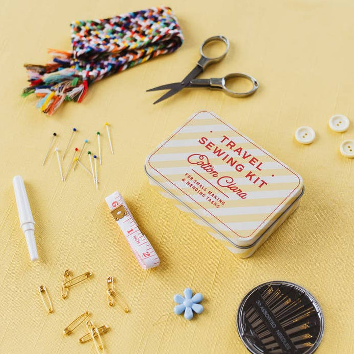 Travel sewing kit with scissors, thread, and other supplies on a yellow background