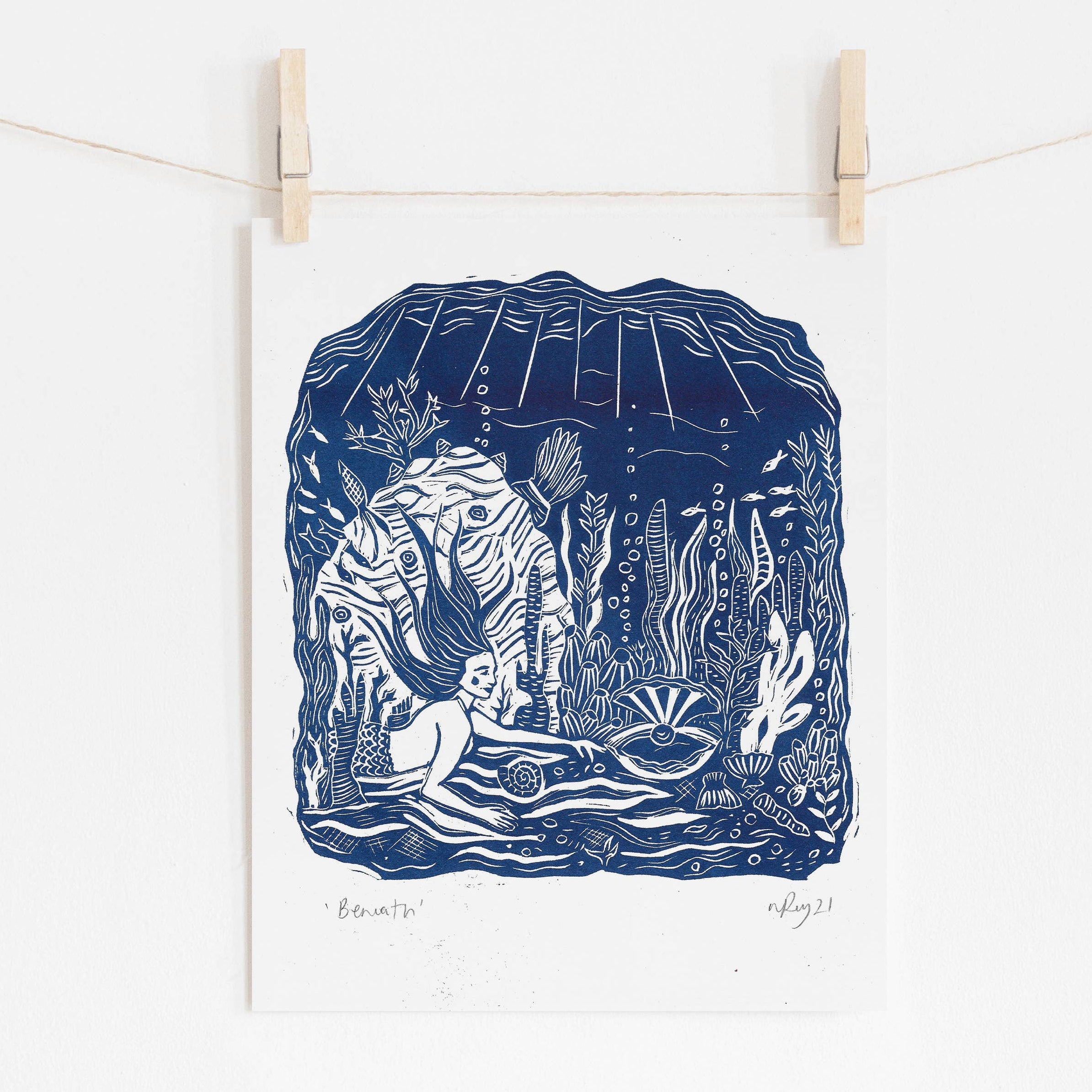 Blue and white illustration of a nature scene hanging on a string with wooden clips against a white background.