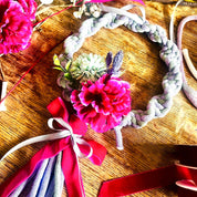 Floral headband with pink flowers and ribbons on a wooden surface