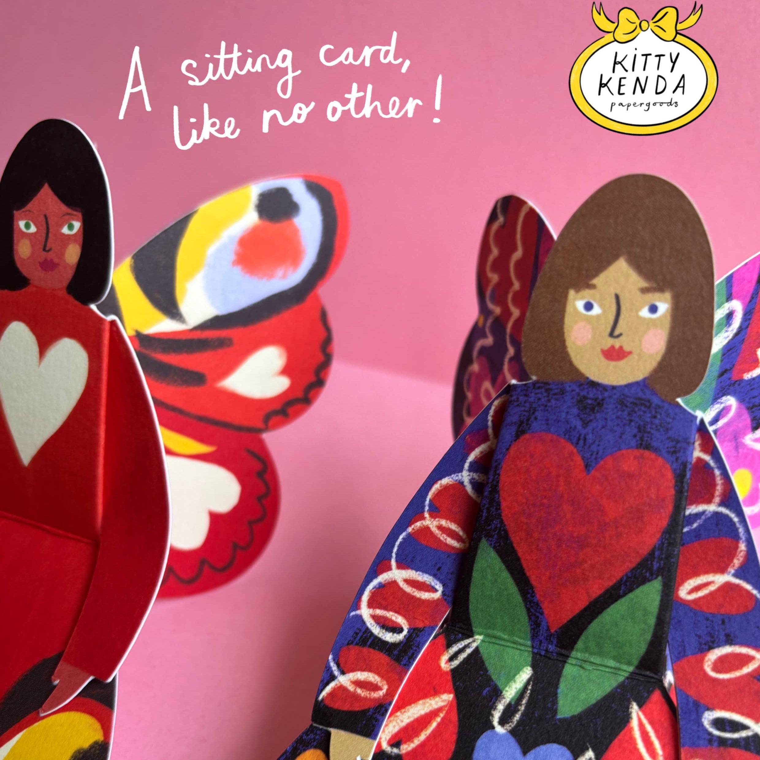 Colorful paper dolls with a butterfly and text on a pink background, featuring the Kitty Kenda brand.
