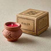 Terracotta candle holder with a lit candle next to a 'DALIT' branded box on a beige background
