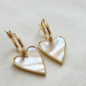 Heart-shaped earrings with gold frames on a light gray background