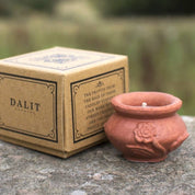 Terracotta candle holder with 'DALIT' branding on a stone surface