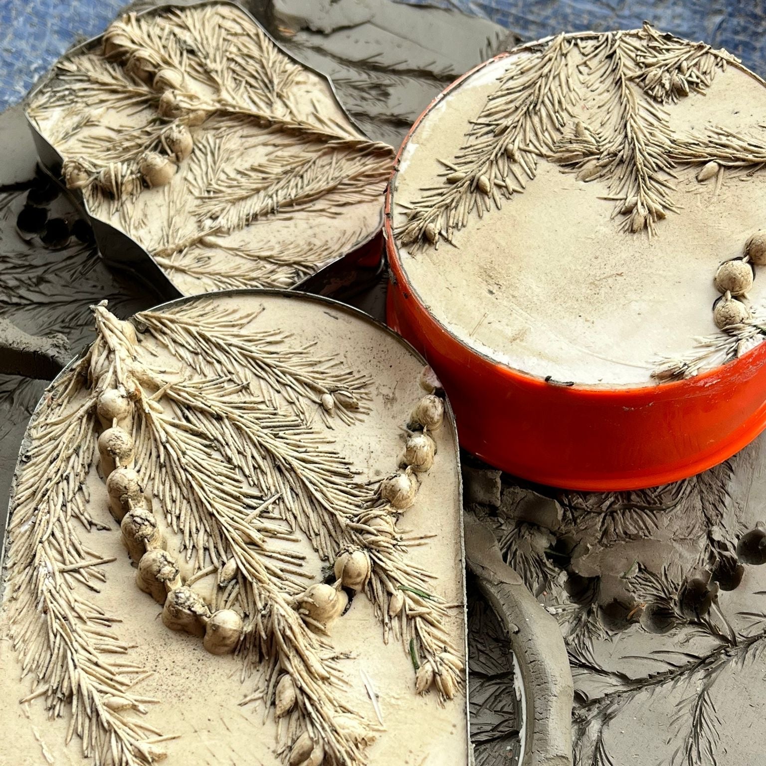 Decorative soap with leaf design next to a red container on a textured surface