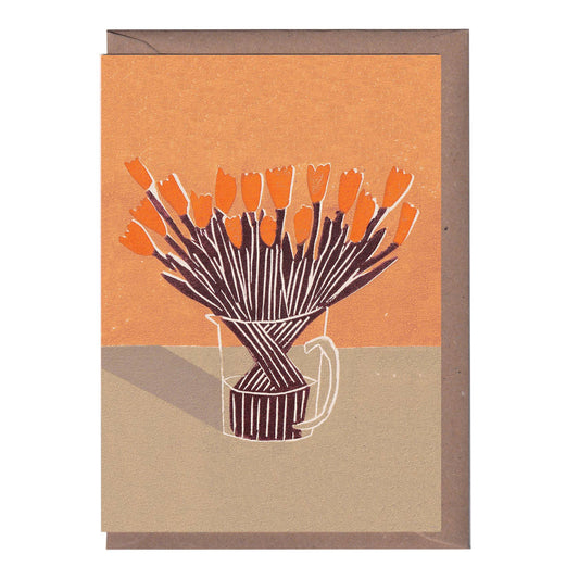 A greeting card featuring a linocut print of an orange tree in a vase, with a beige background and a kraft envelope.